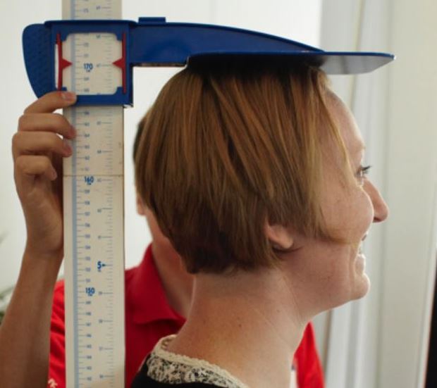 a woman smiling as a Health at Work adviser measures her height