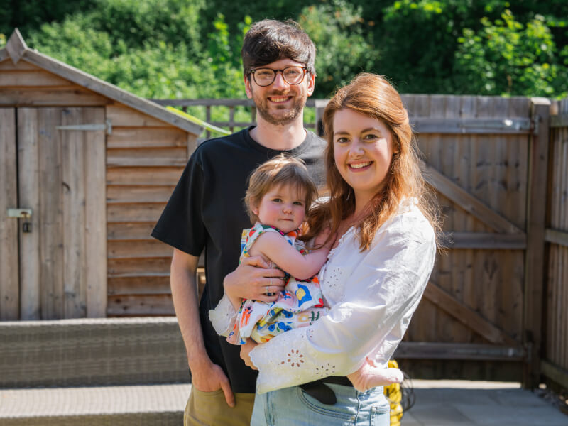 Orla is being held by her mother while her father stands behind them