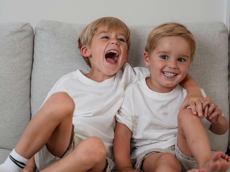 Two children named Lennox and Sonny smiling sat on a sofa