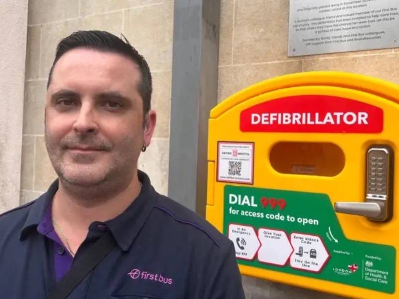 Carlos standing next to wall-mounted defibrillator