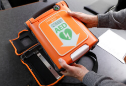 Hands holding an automated external defibrillator