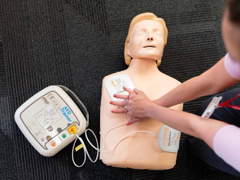 Person practising CPR compressions on a manikin