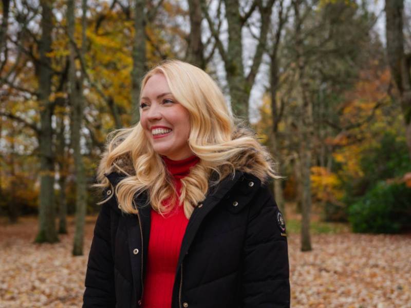 Donna, who survived a cardiac arrest, standing in a forest smiling