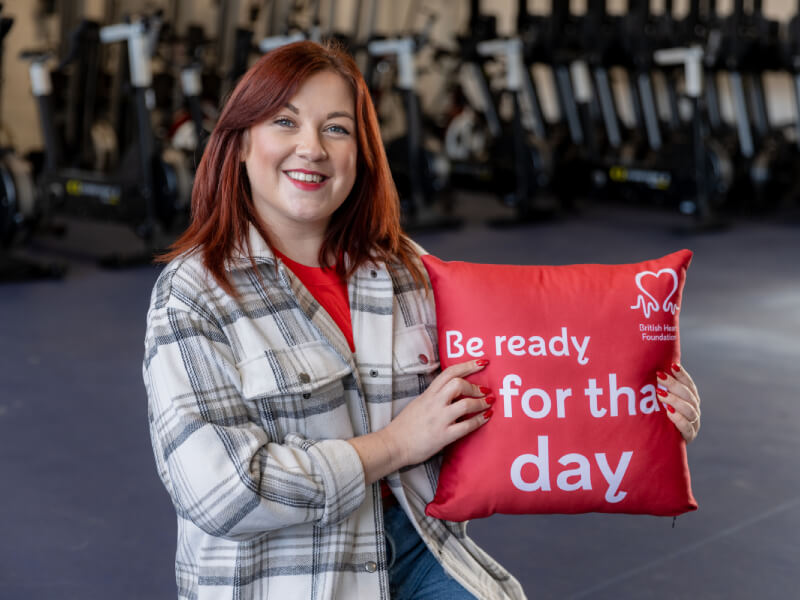 A woman holding a cushion that says 'Be ready for the day'