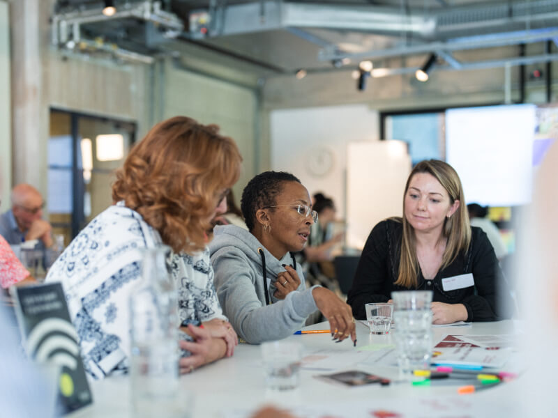 Three members of the Heart Voices community sat on a table having a discussion