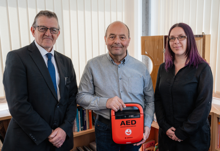 Barry holding a defibrillator in a school