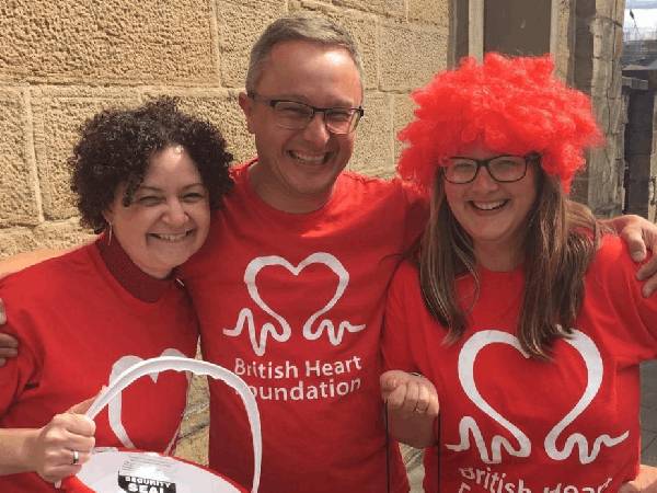 3 people wearing BHF t-shirts holding collection buckets.