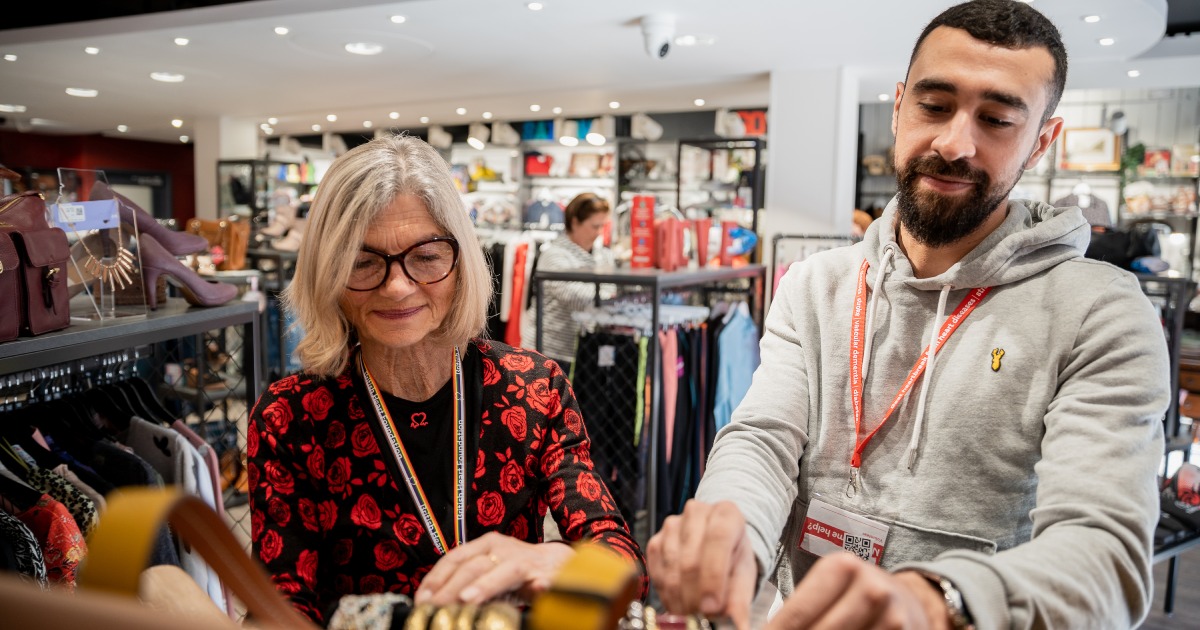 Two of our BHF volunteers working together to hang up clothes in one of our shops.