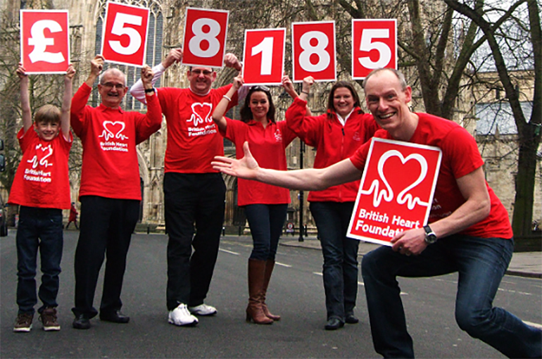 Group of volunteers holding cards to illustrate they have raised £58,185 for the BHF