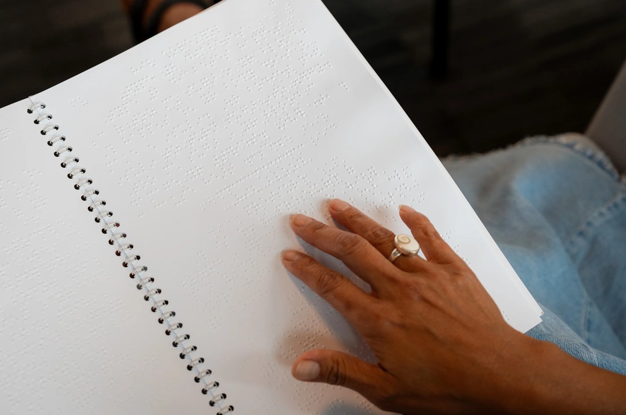 a close up image of a black woman's hand touching a braille booklet
