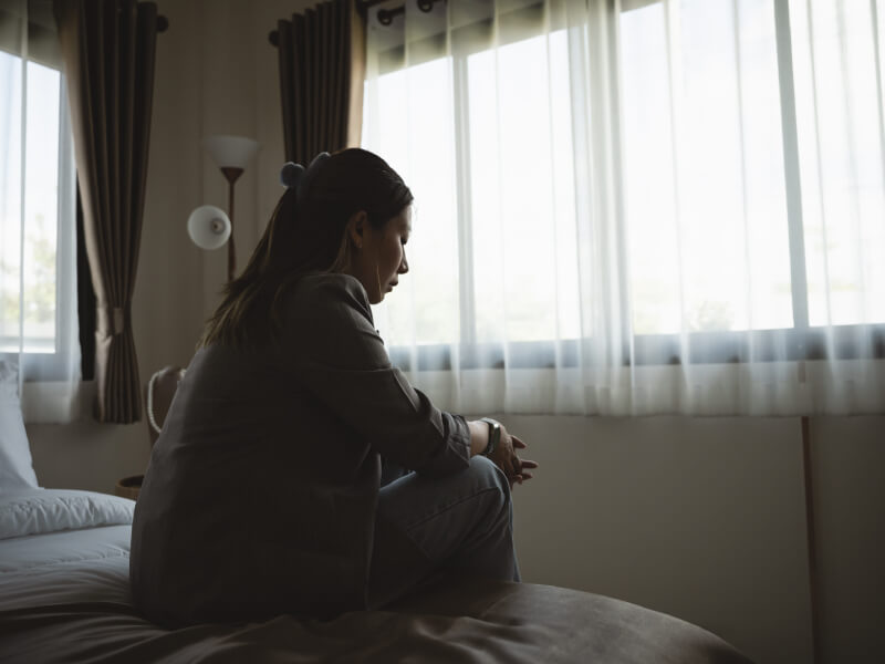 A woman sat on a bed looking down