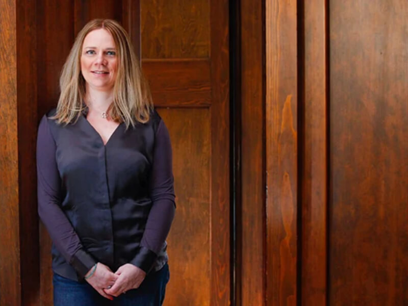 A woman standing in front of a wooden door smiling