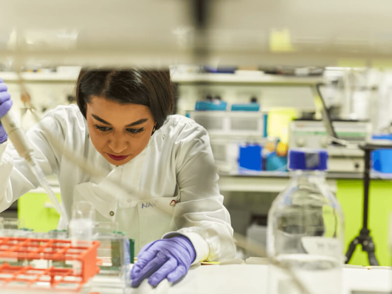 A lab researcher focusing on small vials filled with liquid