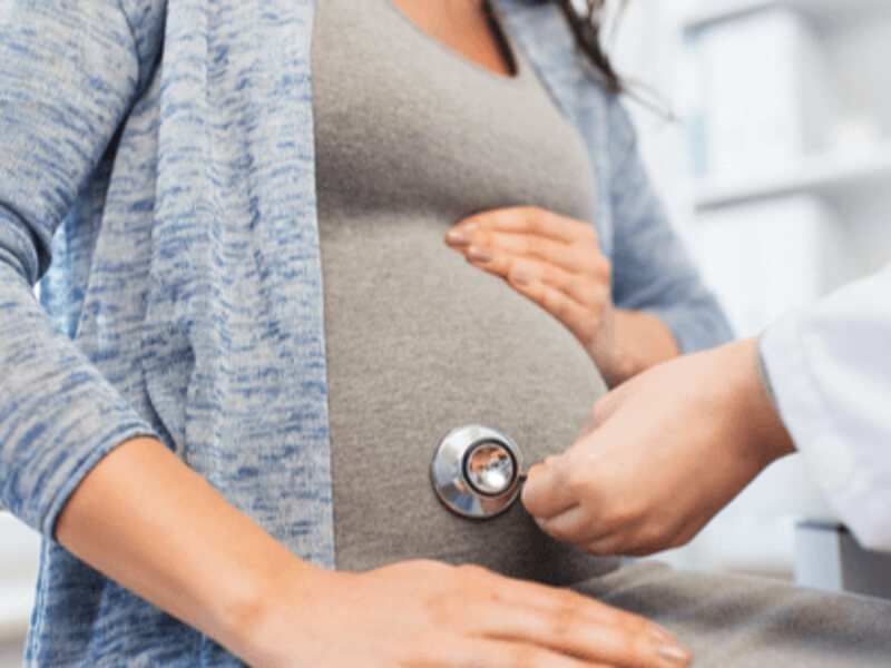 A doctor using a stethoscope on a pregnant woman's stomach