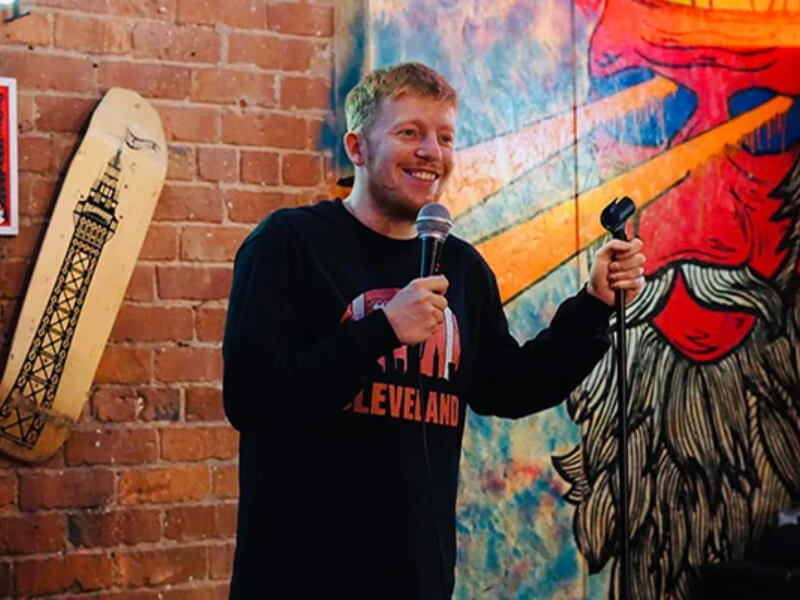 A man with a microphone standing and smiling