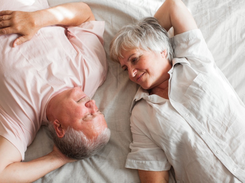 Top view of a senior couple lying on a bed looking at each other.