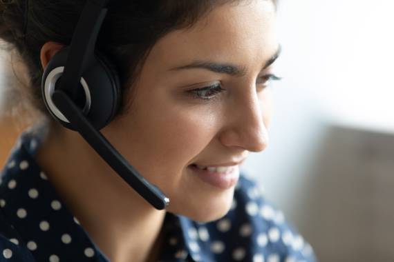 close up image of a dark haired woman wearing a headset and smiling
