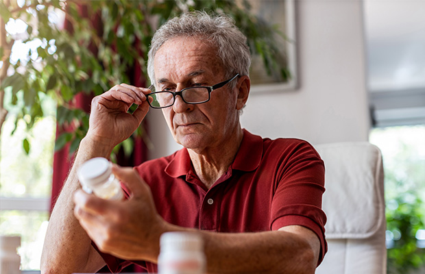 A man holding a medicine bottle and reading the label.