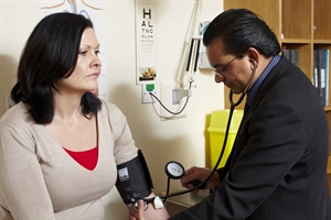 A doctor uses a stethoscope and blood pressure monitor to take a woman's blood pressure