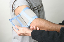 A doctor straps a blood pressure monitor onto a man's arm.