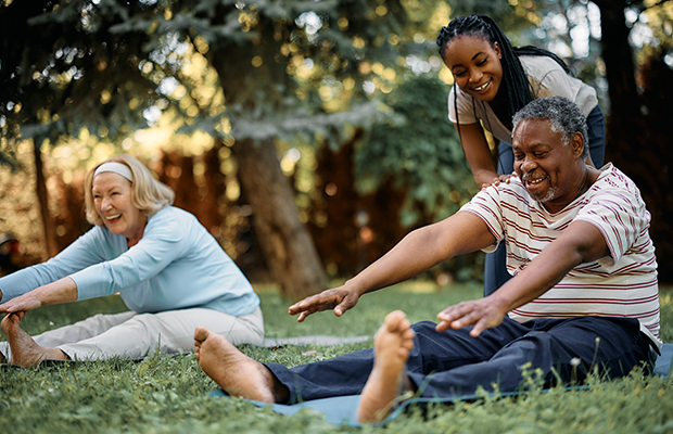 Seniors stretching in the park with a personal trainer