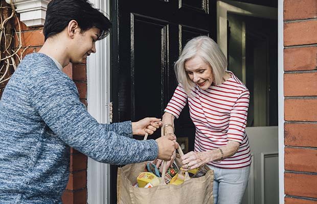 Teenage boy handing woman bags of shopping