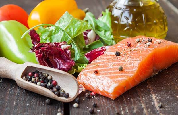Salmon, oil, lettuce and peppers on a wooden surface