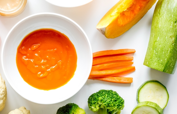 Colourful vegetables around a bowl of soup