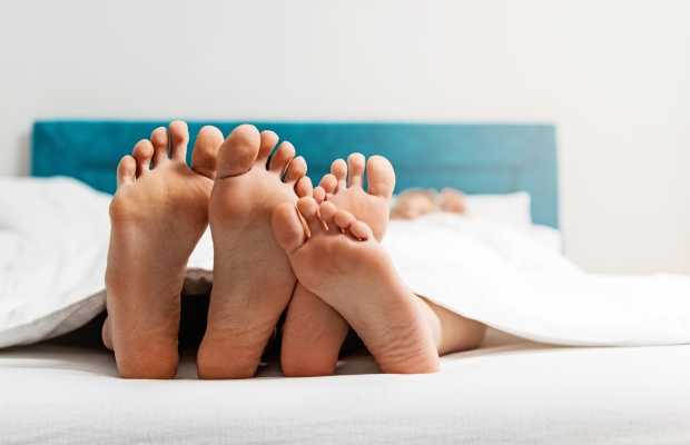 Two pairs of feet in bed