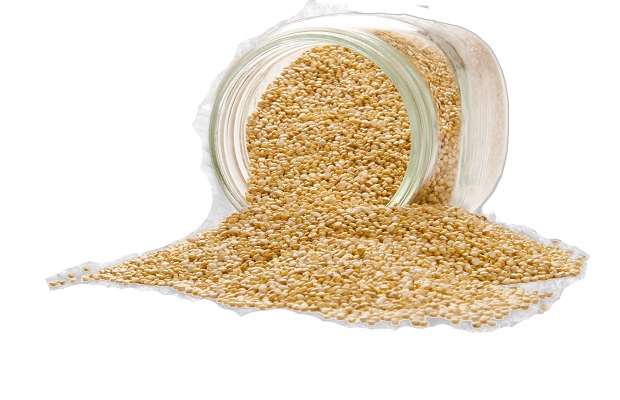 Quinoa spilled out of a clear glass jar isolated on a white background.