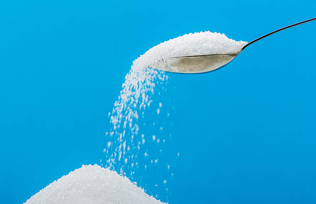 White sugar pouring off a spoon