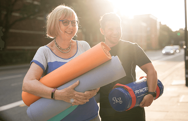 Man and woman carrying yoga and exercise equipment