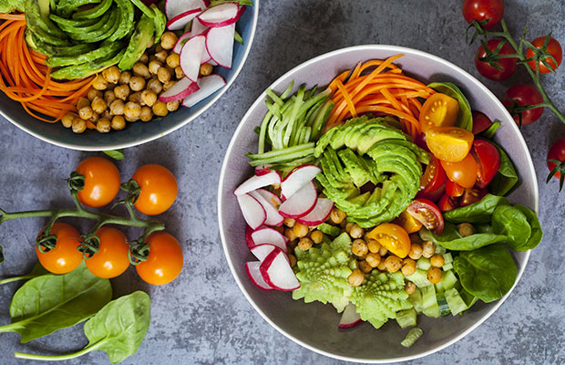 Buddha bowl of mixed vegetables including avocado, carrots and spinach.