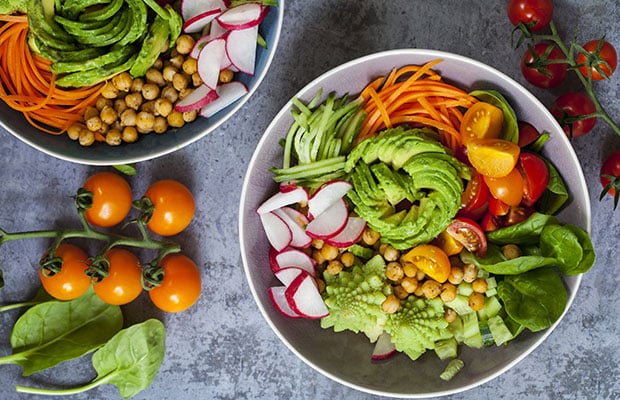 Buddha bowl of mixed vegetables including avocado, carrots and spinach.