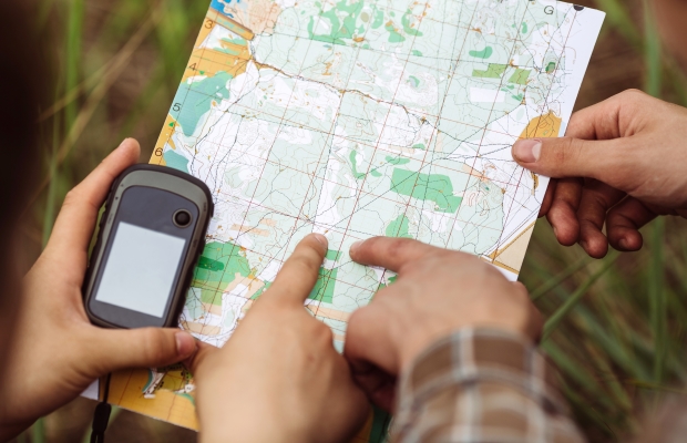 hands holding a map and a GPS
