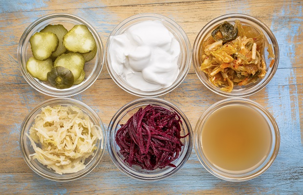 Six pots of fermented foods, on a wooden table