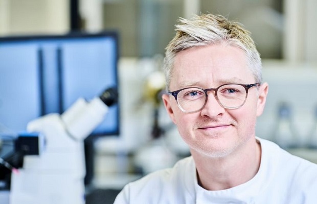 Male research technician next to a microscope