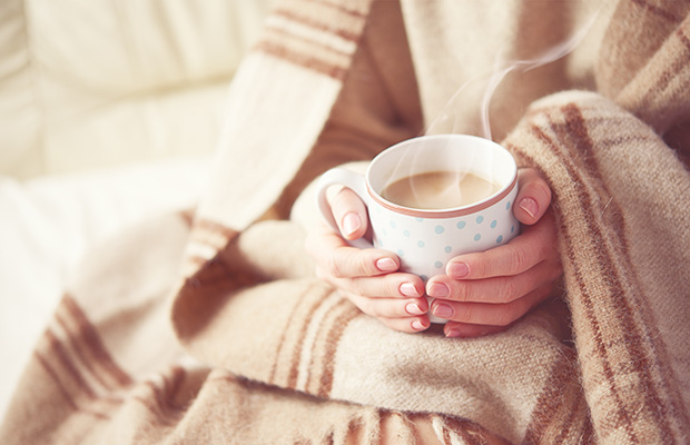 Woman holding coffee in blanket