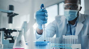 A lab worker presses a pipette in a test tube