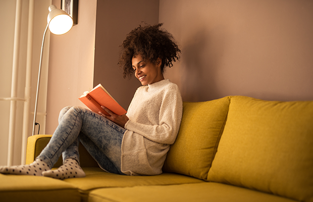 Woman reading a book under a lamp