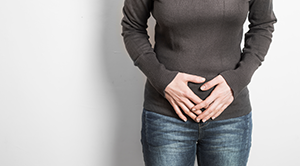 Person holding hands clutching over abdomen 