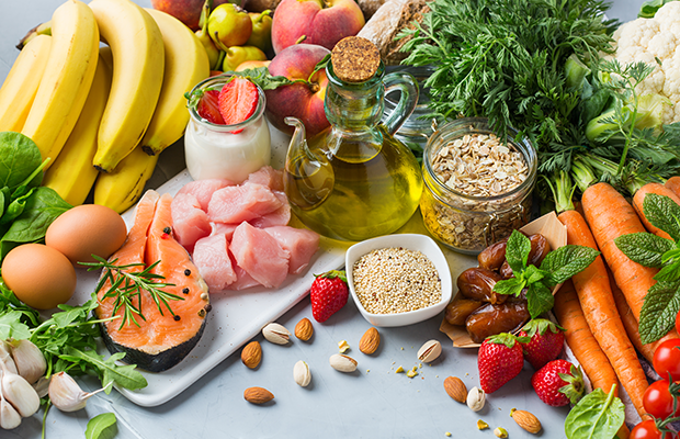 Mediterranean diet ingredients on a table, including fruit, vegetables, olive oil, fish and nuts