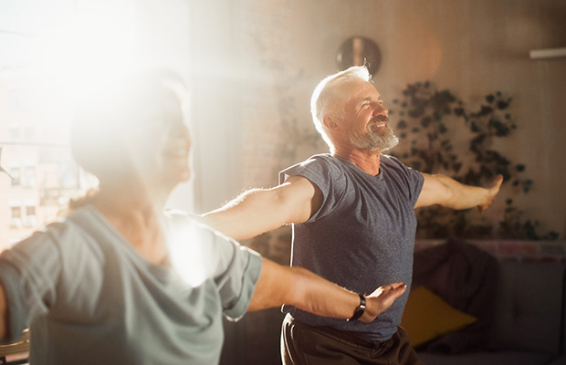 Two people doing jumping jacks at home together