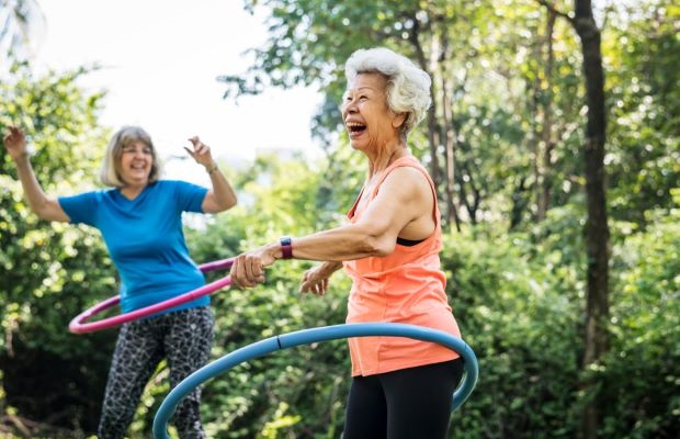 Two women are outside exercising with hula hoops.