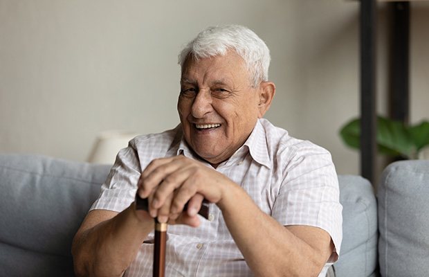Elderly man with a walking stick smiling