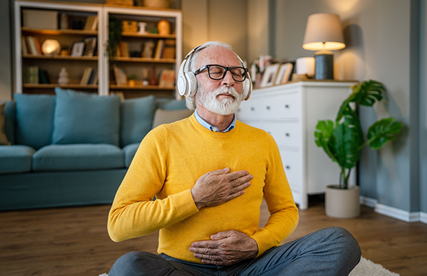 Person sitting calmly in a lotus position with eyes closed, one hand on the chest and one hand resting on the abdomen.