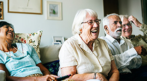 Group of older adults sitting on the sofa laughing.