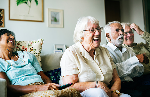 Group of older adults sitting on the sofa laughing.