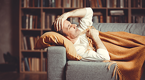 Photograph of a sick looking man lying down on the sofa
