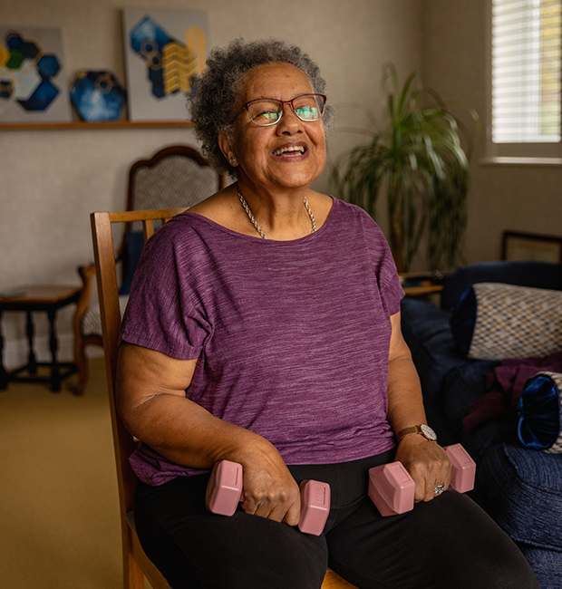 Photograph of Laraine holding dumbbells while smiling at the camera